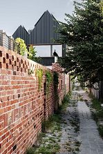 Photo looking along patterned brickwork bordering the laneway, towards the house in the background.