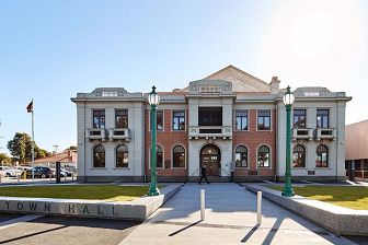 An exterior photograph of the Williamstown Town Hall on a bight sunny day from a front aspect showing the forecourt and grass lawn.