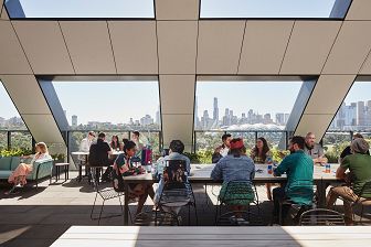 View of people enjoying the level 6 outdoor terrace space at SEEK HQ. Several people are sitting at the outdoor tables and the view of the city is in the background