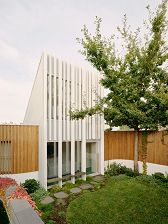 An image from the courtyard looks at a modern white house flanked by timber fencing.