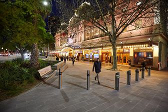 An evening scene featuring a wide forecourt in front of illuminated Princes Theatre.
