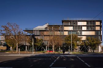 external elevation view of the school with sun shining on the façade which is shaded by large vertical louvres