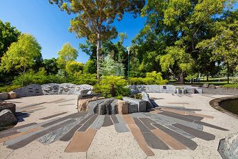 Quarried and sawn stone types, of different surface texture and pigmentation, are arrayed on the ground plane and form central and edge planting. These gardens feature tree ferns and distinct eucalypt species.