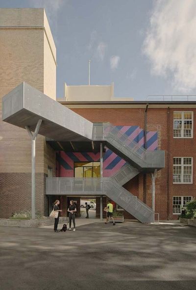 Exterior of a building with external staircase and a mural painting by Reko Rennie.