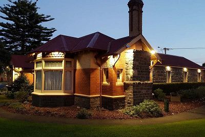 Dusk exterior of a single storey bluestone and redbrick homestead building with timber framed bay window, whose design dates back to the mid-1840s.