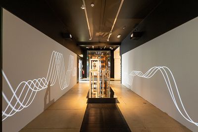 Photograph of recreated Free Music Machines. To the side of the objects are projections of visuals that respond to the sound waves of the instruments. This room is part of the Grainger Amplified exhibition.