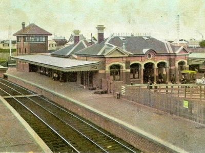 Aerial view of Footscray Railway Station showing platform 3 and train lines heading north and south. Building is red bricked and there are a few people in the station forecourt.