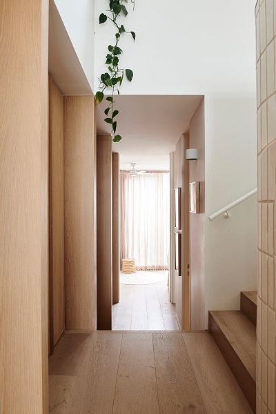 Photograph of internal corridor with oak joinery on the left, staircase to the right and sheer curtained windows of the bedrooms beyond.
