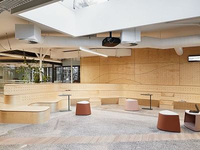 Photo shows the interior of a small auditorium, with three tiers of timber seating and exposed ducts across the ceiling.