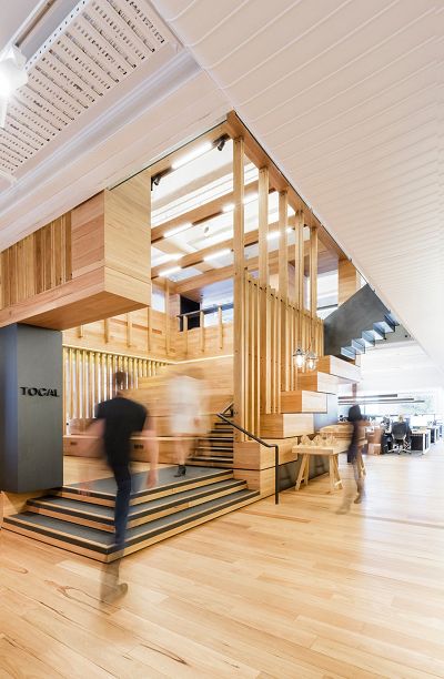 Interior shot of the studio, with vertical wooden elements forming a big open box, with a staircase leading up through the open space.