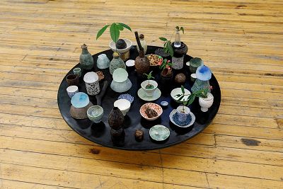 1. A low circular table crowded with hand built ceramic bowls, vases, vessels holding plants flowers and other sculptural objects viewed from above.
2. A wooden wall shelf with found objects and small hand built stoneware vessels, some holding plants, seedlings, stones and twigs. 
3. Emely Baker Centre entrance.
4. Close up of the plaque in foyer. CITY OF FITZROY
EMELY BAKER INFANT WELFARE CENTRE
THIS BUILDING WAS OPENED BY THE MAYOR CR.EILEEN J. WHEELER, J.P.
3RD DECEMBER, 1971. K.MURRAY FORSTER & WALSH, ARCHITECTS.