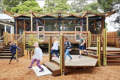 The Fives classroom building with extended deck areas at three different levels, with  children running along the deck.