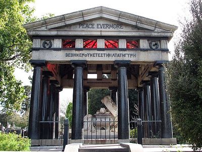 Image shows an elaborate Victorian era memorial, built in a neoclassical style with a series of Doric columns supporting the slanted roof over the grave. On the roof is a sign that reads 'Peace Evermore.'