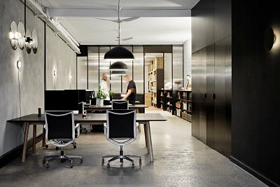 A long office space with concrete floor and black wall.