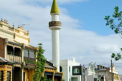External of the Albanian Mosque which shows the stone coloured rendered minaret with a golden cone domed top. This is the high tower where the call to prayer is made in Islamic countries. It is a symbol of Islamic architecture and also the importance of prayer.