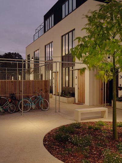 A photo of a central courtyard shows bikes leaning on a fence and a set of contemporary townhouses in the background.