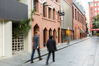 Two people walking along a laneway with varied architectural forms and materiality