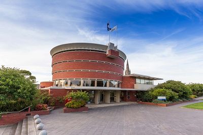 Colour photograph of a circular shaped, red brick, modernist building with blue sky in the background.