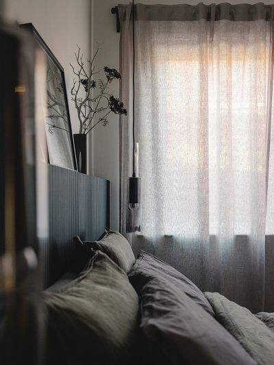 Image of a bedroom from across the bed looking at a window with curtains. Suspended light