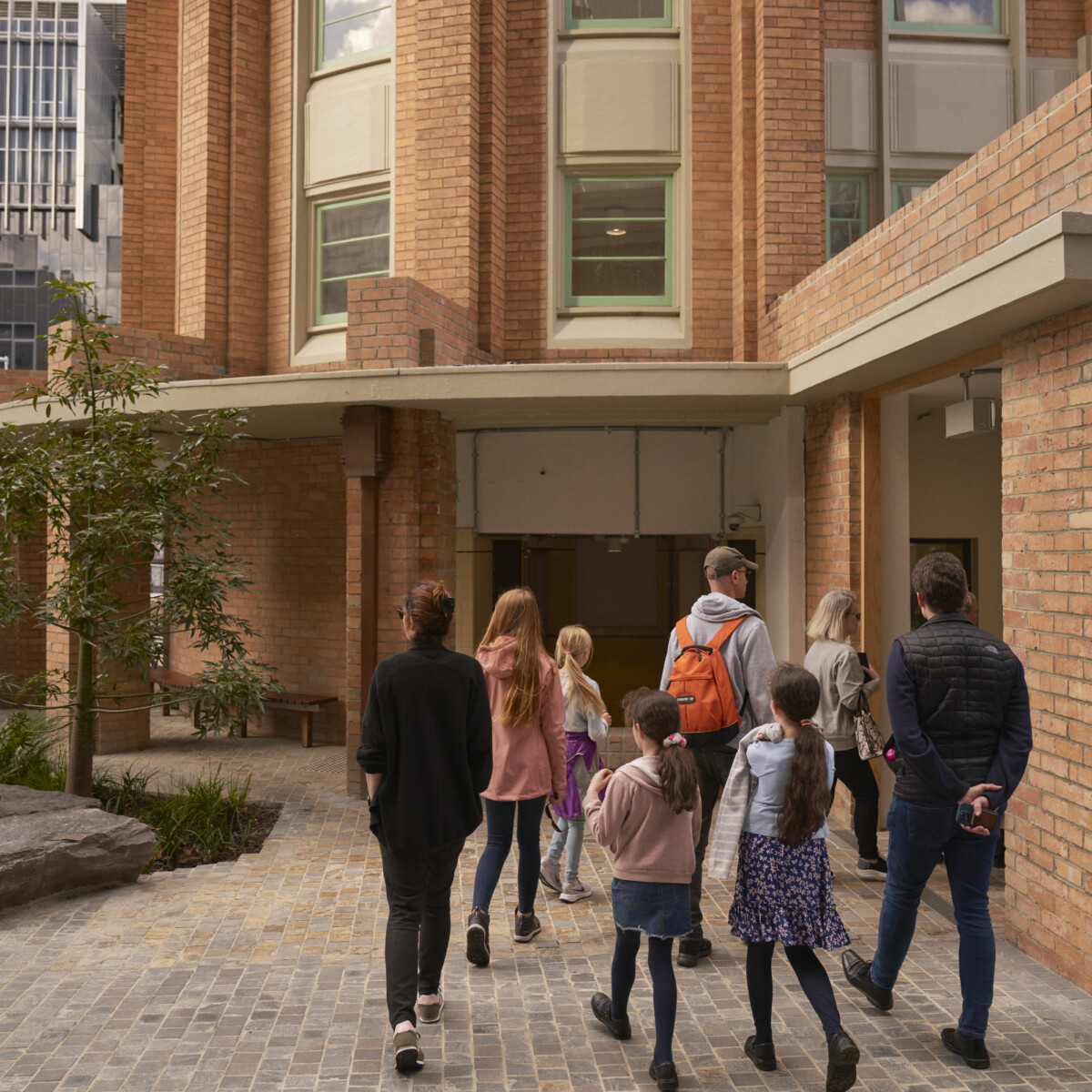 A small group of people walk into a red brick building.